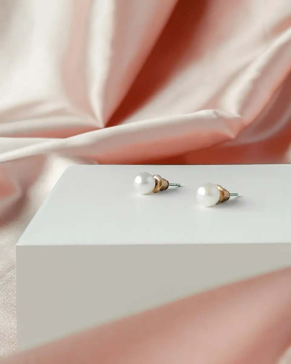 a pair of pearl earrings sitting on top of a white box